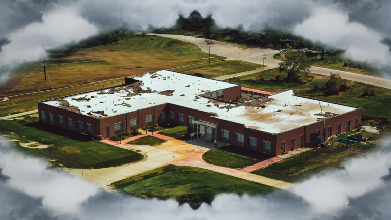 Aerial view of a school with a flat roof, damaged from a tornado.