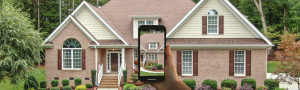 House with hand holding cell phone recording a video of the house
